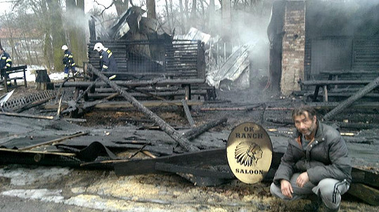 Zničený Honza Pokorný před vyhořelým srubem na svém ranči.