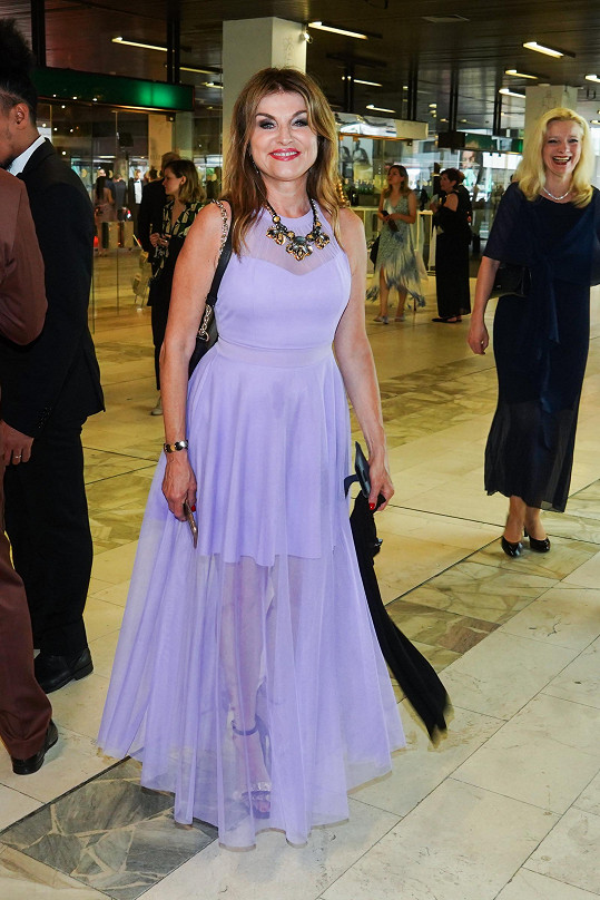 Simona Prasková v lila šatech, které nepochopitelně doplnila obřím šperkem.